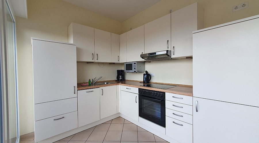 Essbereich mit Obstkorb und offenem Wohnzimmer mit roten Sitzmöbeln